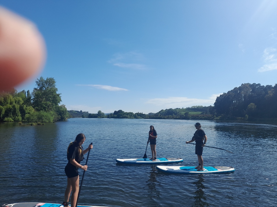 Sup schools a group of people standing next to a body of water